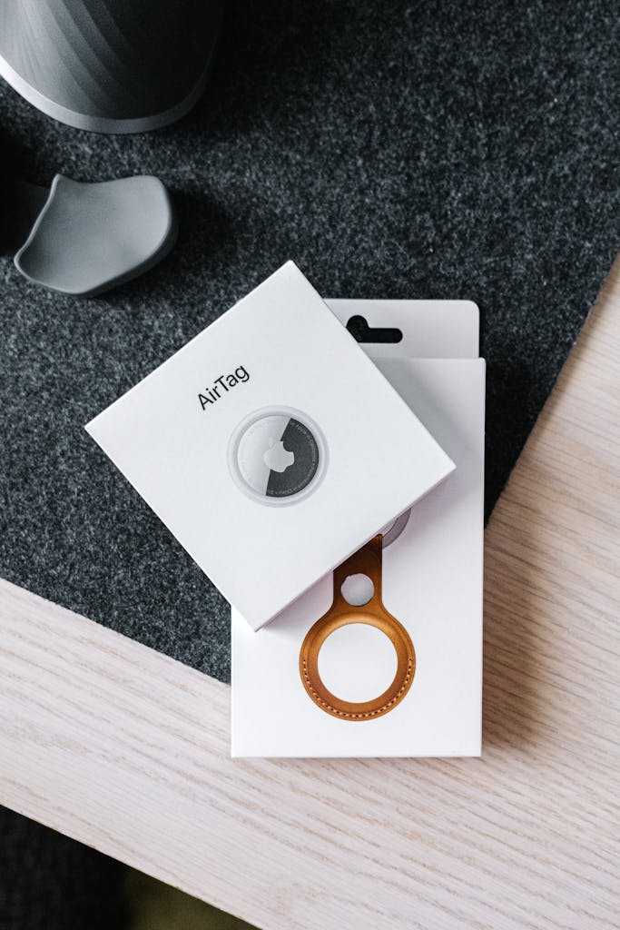 Overhead shot of AirTag and leather key ring packaging on wooden surface.